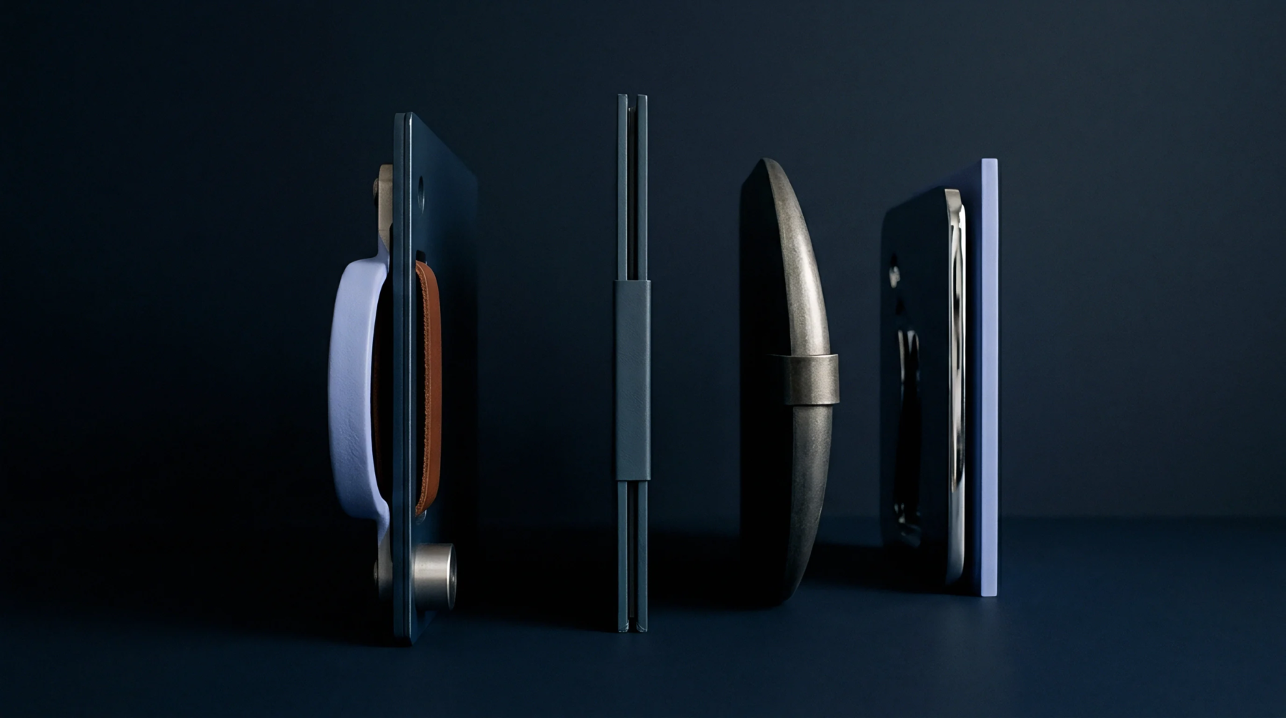 Four minimalist product prototypes stand in profile against a solid dark surface displaying structural variations in packaging materials and assembly methods.