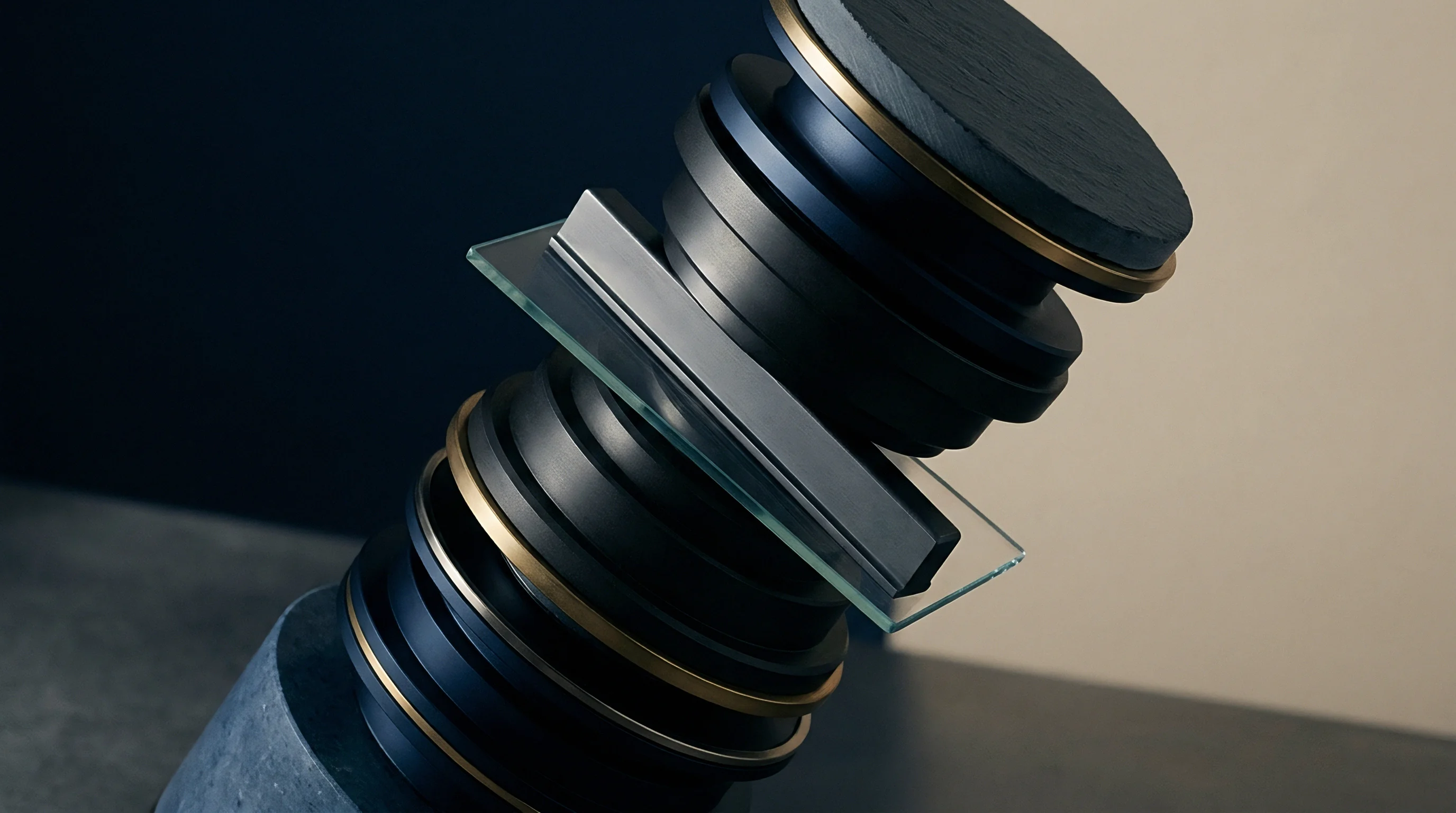 A stacked arrangement of circular dark material discs with metallic bands and a transparent glass sheet sits atop a cylindrical concrete support.